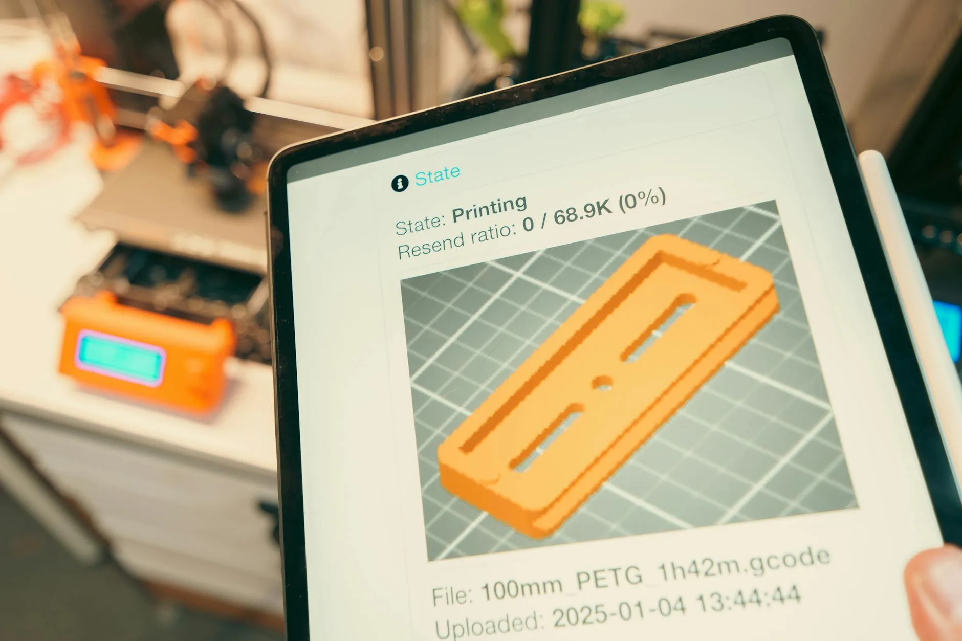 Tablet pokazujący proces druku 3D w małym warsztacie usługowym