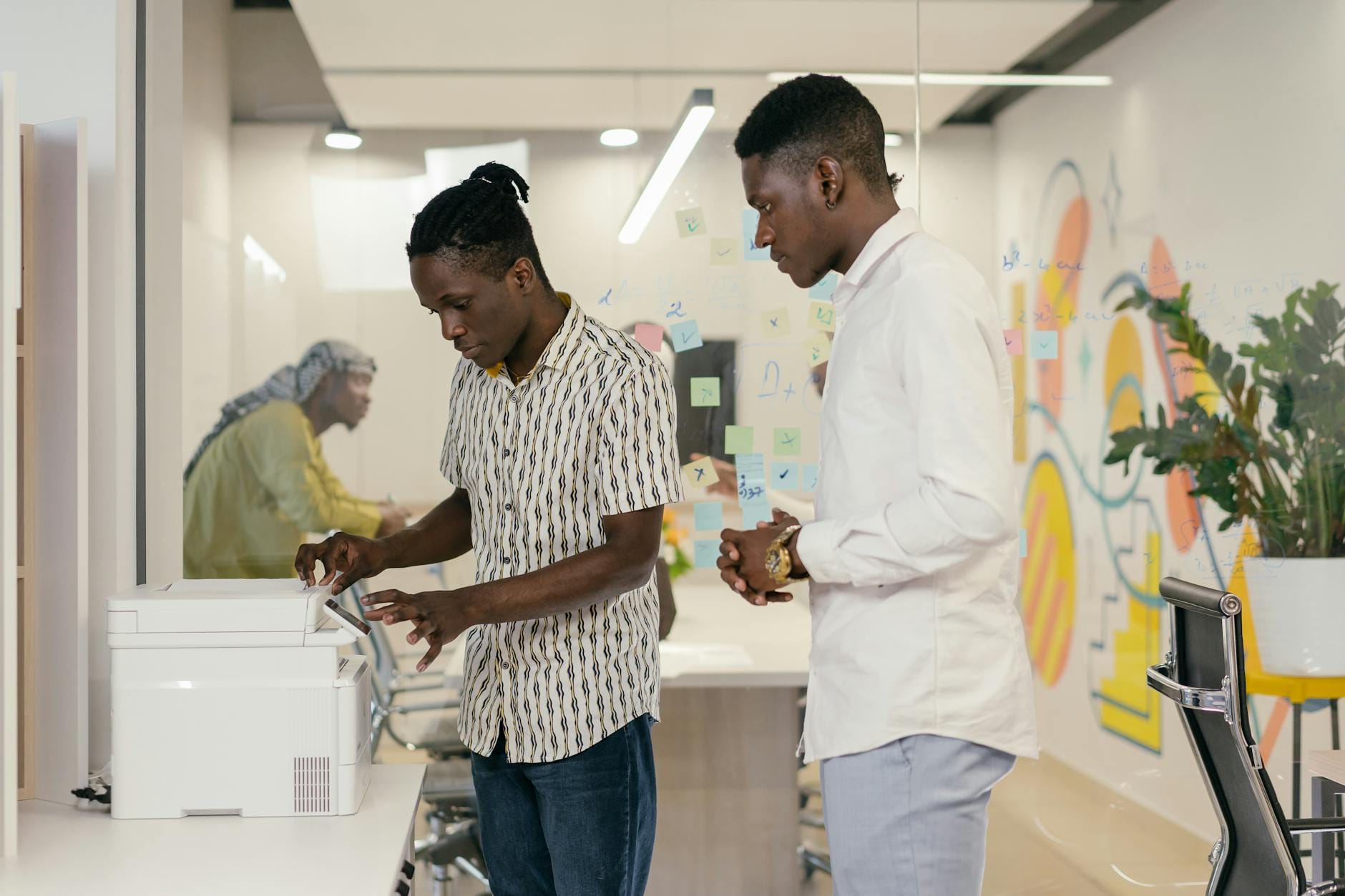 Pracownicy biura wspólnie obsługują drukarkę w nowoczesnym biurze